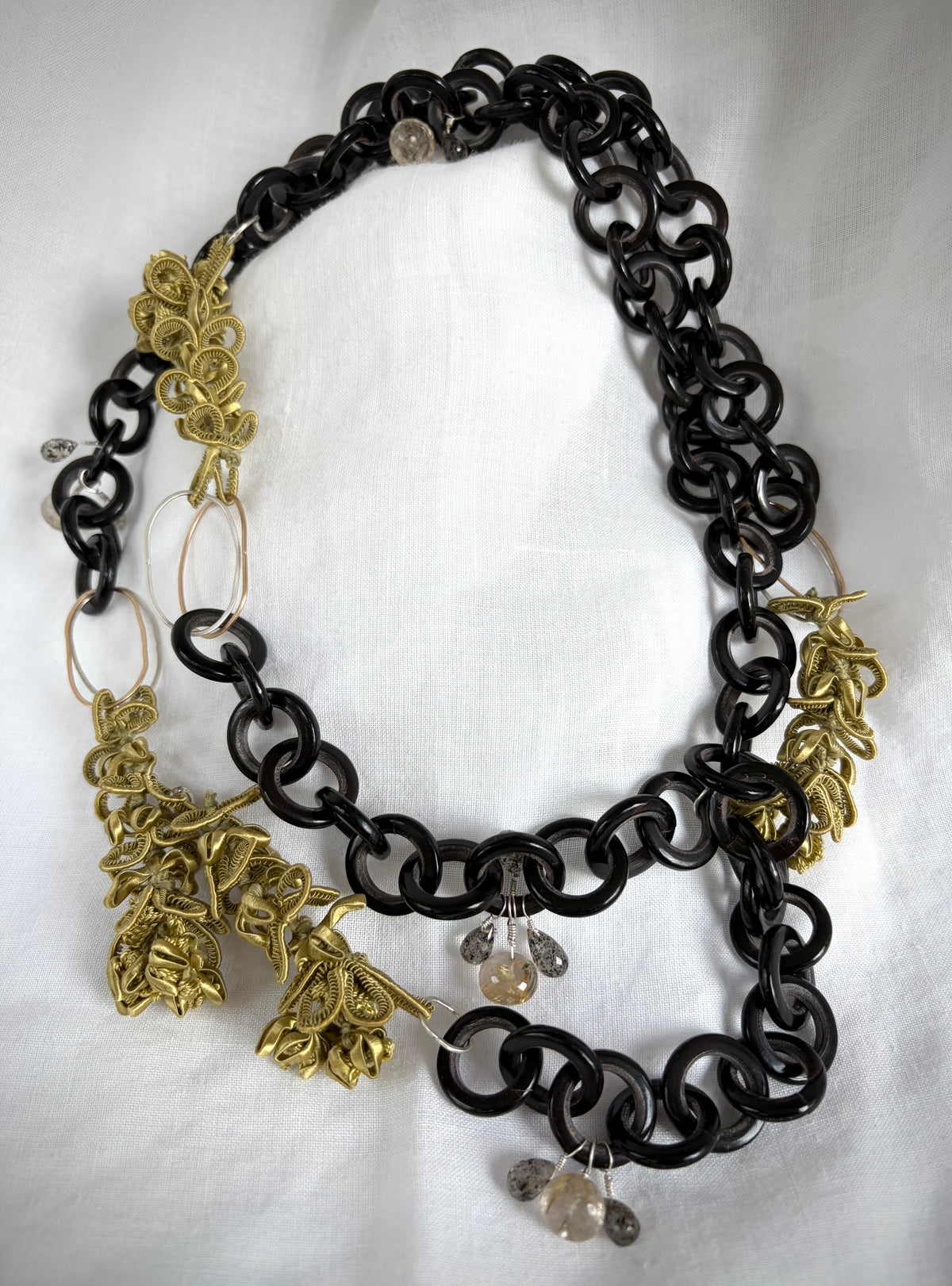 Necklace with black, gold, and silver chain with chartreuse silk jasmine  decorative pendants on a white background.