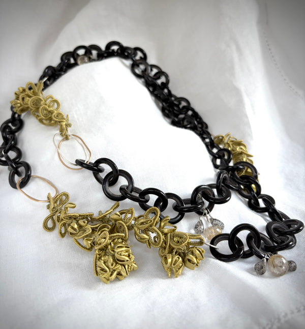 Necklace with black, gold, and silver chain with chartreuse silk jasmine  decorative pendants on a white background.