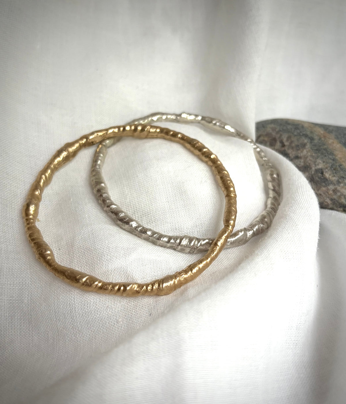 Gold and silver necklace with five golden rutile  quarts charms resting on a flax-colored fabric background