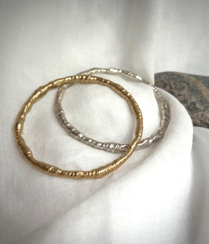 Gold and silver necklace with five golden rutile  quarts charms resting on a flax-colored fabric background